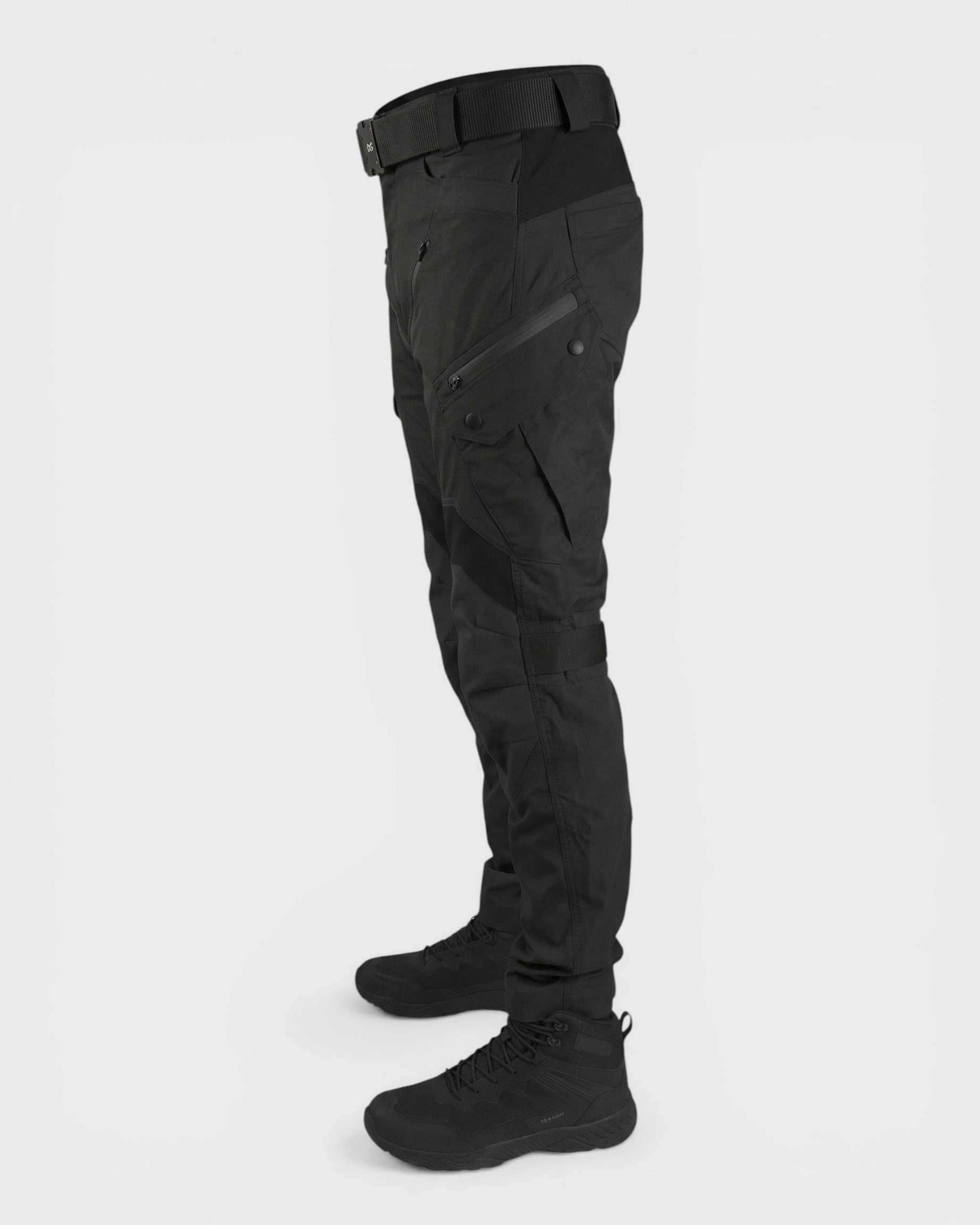 Alexandra Oradea Albert black tactical utility pants with multiple zippered pockets and adjustable ankle straps.